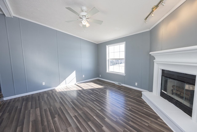 unfurnished living room with dark hardwood / wood-style floors, rail lighting, ornamental molding, ceiling fan, and a textured ceiling