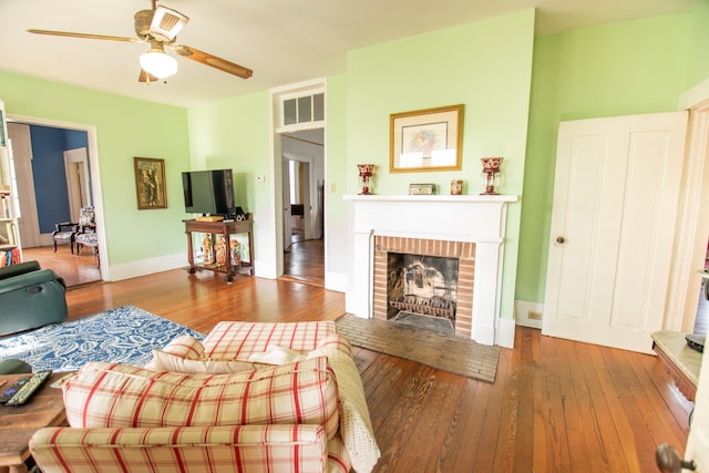 living room with a fireplace, wood-type flooring, and ceiling fan