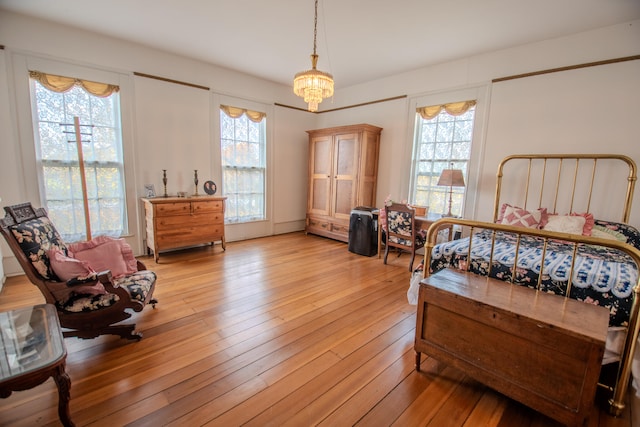 bedroom featuring a notable chandelier, multiple windows, and light wood-type flooring