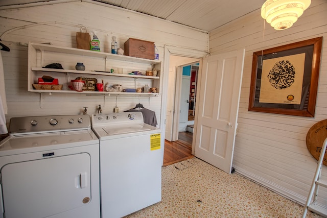 laundry room with light hardwood / wood-style floors, washer and clothes dryer, and wooden walls