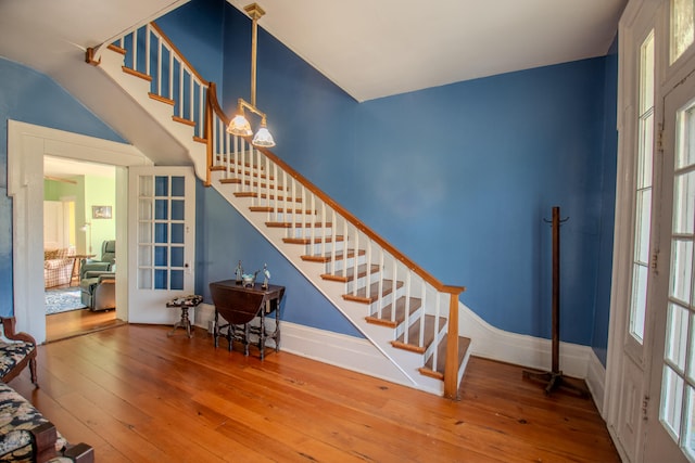 stairs featuring french doors, a healthy amount of sunlight, and wood-type flooring