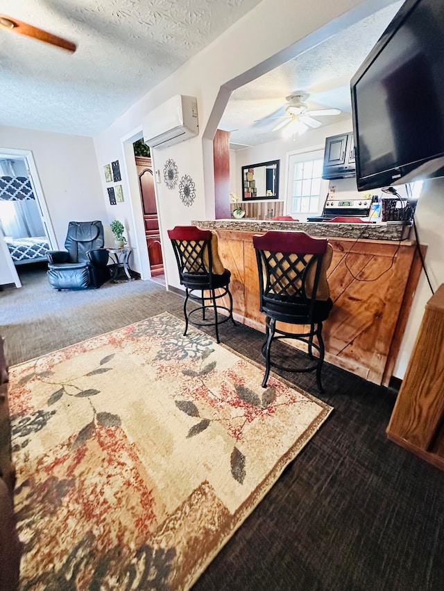 living room with ceiling fan, a textured ceiling, a wall mounted air conditioner, and dark colored carpet