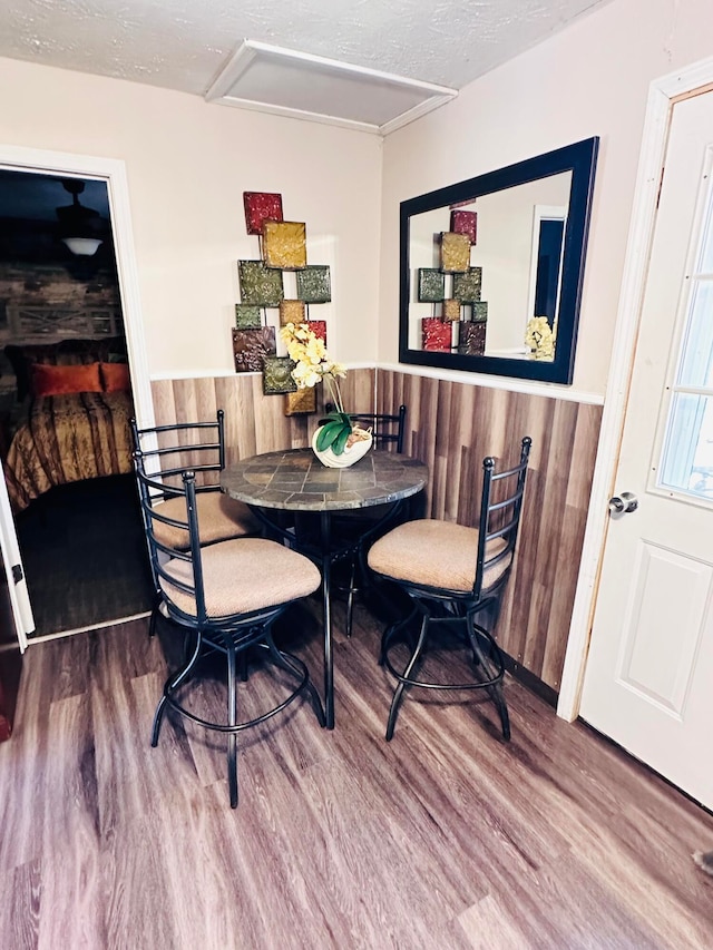 dining room with hardwood / wood-style floors, a textured ceiling, and wood walls