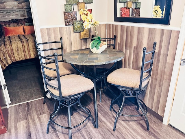 dining area with wood-type flooring and wood walls