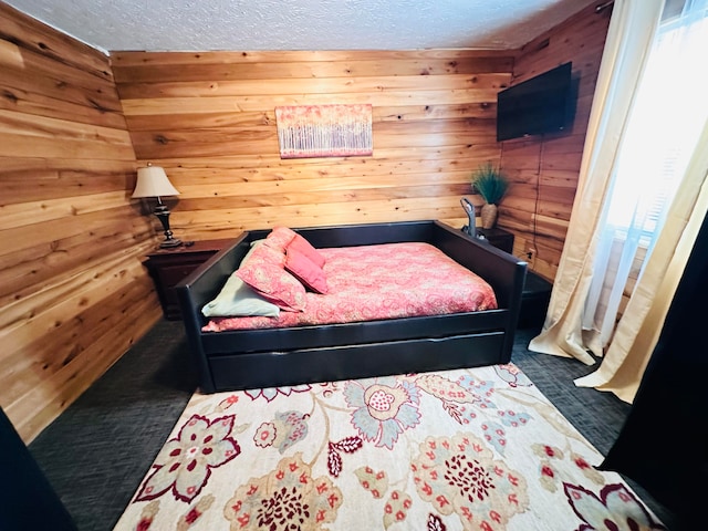 bedroom featuring wood walls, a textured ceiling, and carpet floors