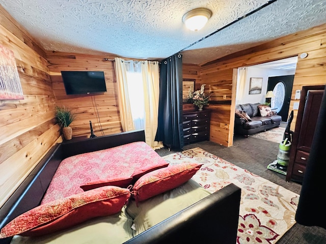 carpeted bedroom with wood walls and a textured ceiling