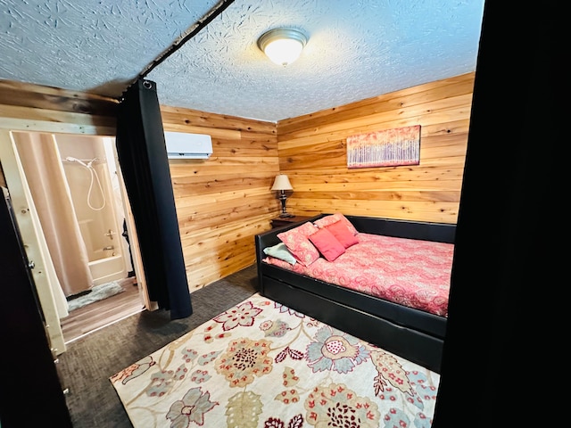 bedroom with dark wood-type flooring, wood walls, a textured ceiling, and a wall unit AC