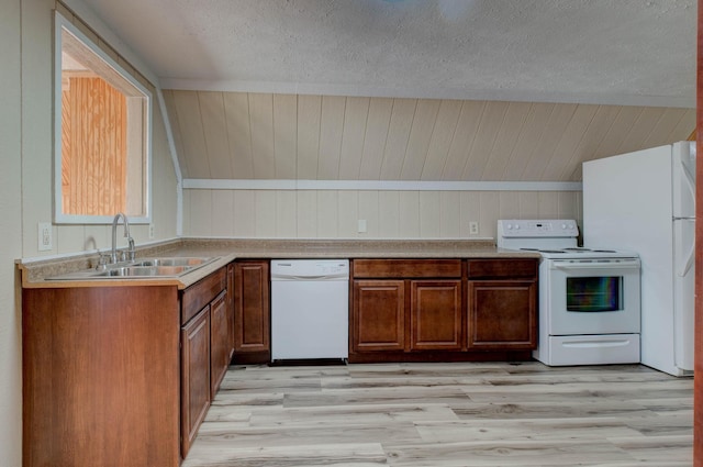 kitchen with a textured ceiling, wooden walls, light wood-type flooring, and white appliances