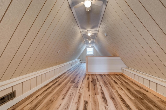 bonus room with lofted ceiling, wooden walls, hardwood / wood-style flooring, and ceiling fan