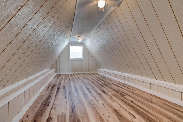 additional living space featuring lofted ceiling, hardwood / wood-style floors, and wood walls