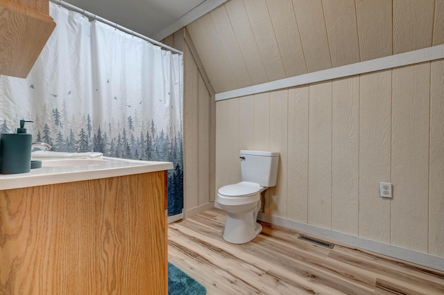 bathroom with lofted ceiling, hardwood / wood-style floors, toilet, wood walls, and vanity