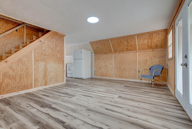 additional living space featuring vaulted ceiling, light hardwood / wood-style flooring, and wooden walls