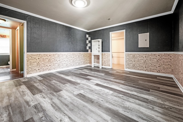 spare room with ornamental molding, electric panel, and wood-type flooring