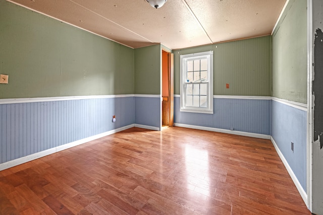 unfurnished room with wood walls, hardwood / wood-style floors, and a textured ceiling