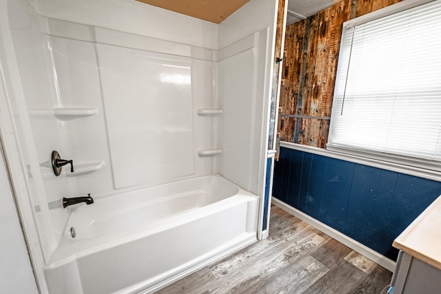 bathroom with vanity, wood walls, hardwood / wood-style floors, and washtub / shower combination