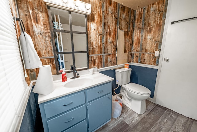 bathroom with vanity, toilet, wood-type flooring, and wooden walls