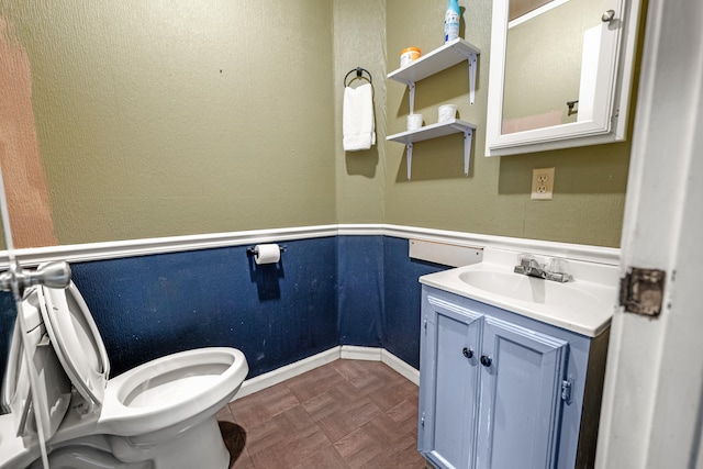 bathroom with vanity, toilet, and parquet floors