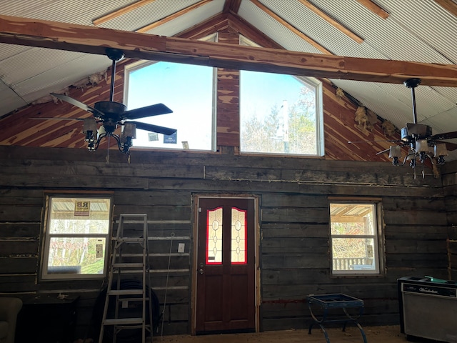 entryway with beamed ceiling, ceiling fan, wooden walls, and high vaulted ceiling