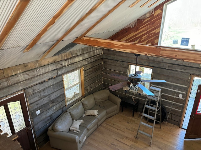 unfurnished living room featuring wood-type flooring, ceiling fan, and wood walls