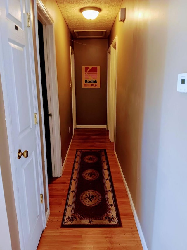 hallway featuring a textured ceiling and wood-type flooring