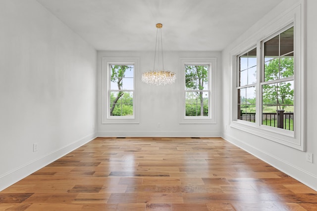 unfurnished dining area featuring a notable chandelier and light wood-type flooring