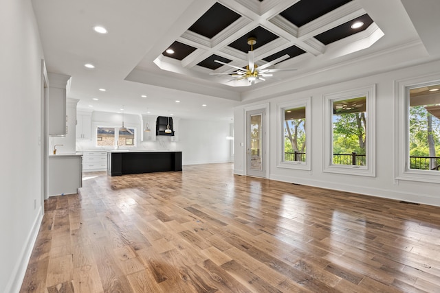 unfurnished living room featuring ceiling fan, light wood-type flooring, ornamental molding, beamed ceiling, and coffered ceiling