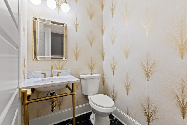 bathroom with toilet, sink, and tile patterned flooring