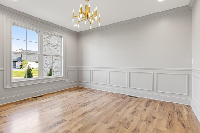 unfurnished room featuring light hardwood / wood-style floors, ornamental molding, and a chandelier