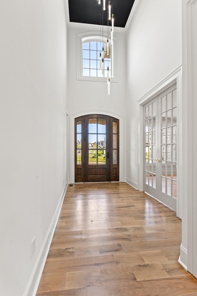 entryway with a wealth of natural light, a high ceiling, light hardwood / wood-style floors, and french doors