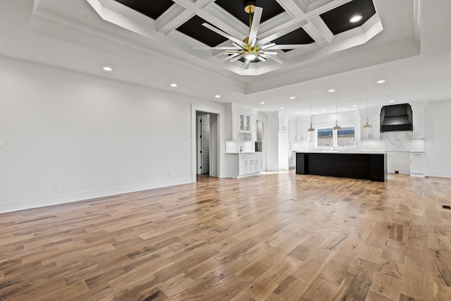 unfurnished living room with ceiling fan, coffered ceiling, ornamental molding, and light wood-type flooring