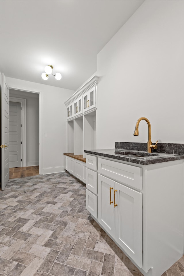 interior space featuring white cabinetry, dark stone countertops, and sink