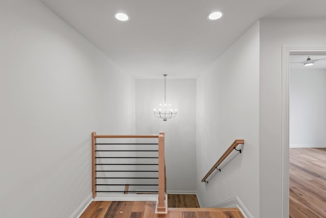 stairway featuring wood-type flooring and an inviting chandelier