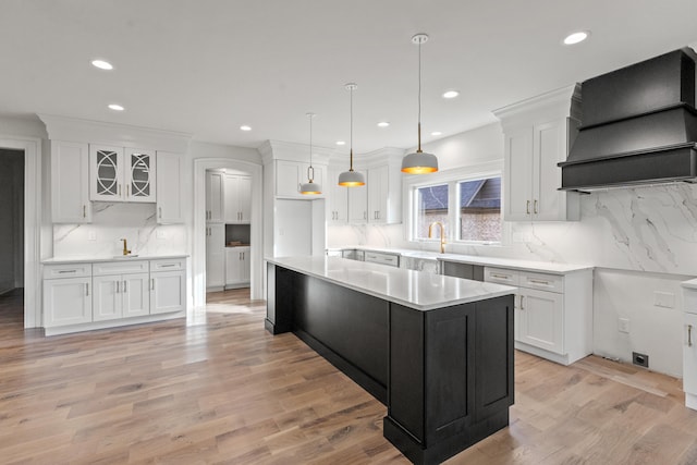 kitchen featuring white cabinets, custom range hood, and light wood-type flooring