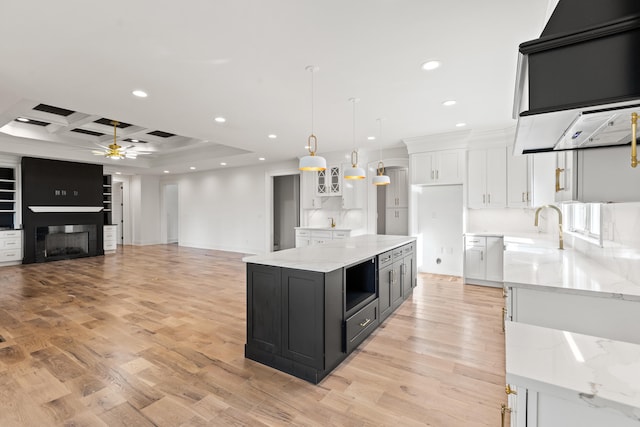 kitchen featuring a spacious island, white cabinetry, ceiling fan, pendant lighting, and light hardwood / wood-style flooring