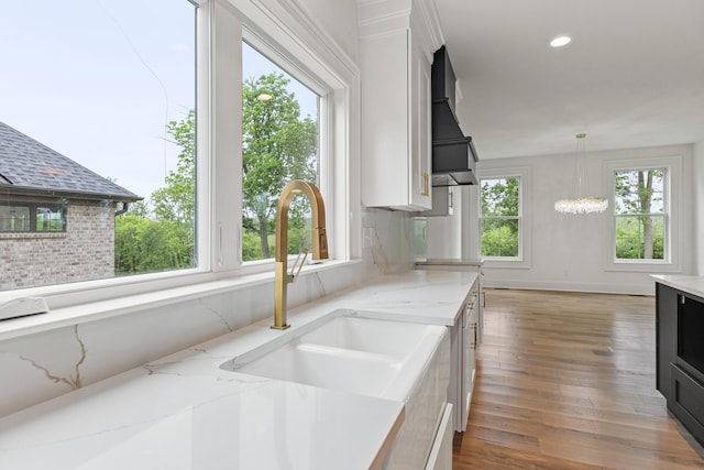 kitchen with light stone counters, decorative light fixtures, and plenty of natural light