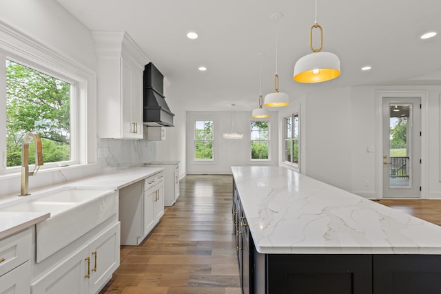 kitchen with sink, a kitchen island, white cabinetry, decorative light fixtures, and custom exhaust hood