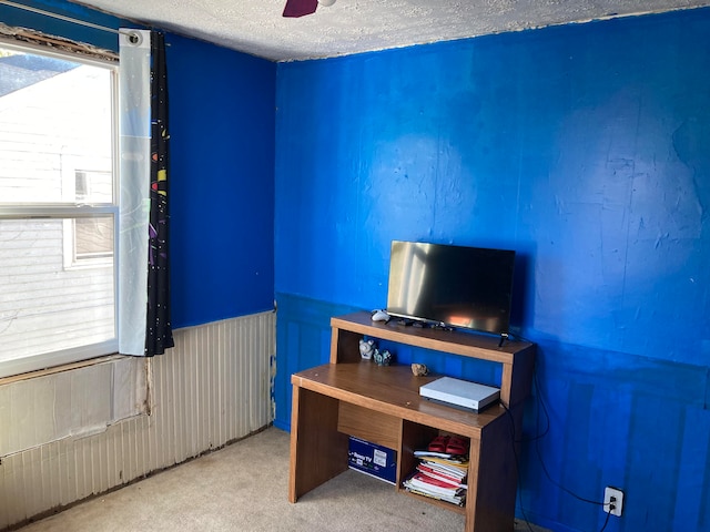 carpeted home office with ceiling fan and a textured ceiling