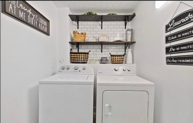 laundry room with a textured ceiling and washing machine and clothes dryer