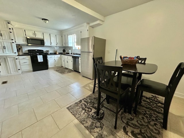 kitchen with white cabinetry, stainless steel appliances, backsplash, and light tile patterned floors