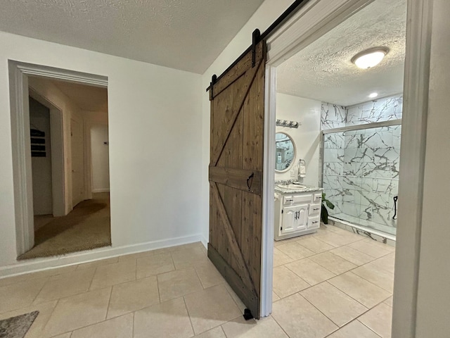 bathroom featuring vanity, a textured ceiling, a shower with shower door, and tile patterned flooring