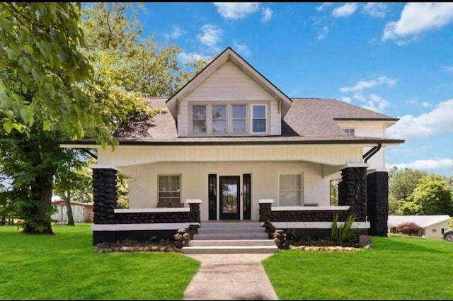 rear view of house featuring covered porch and a yard