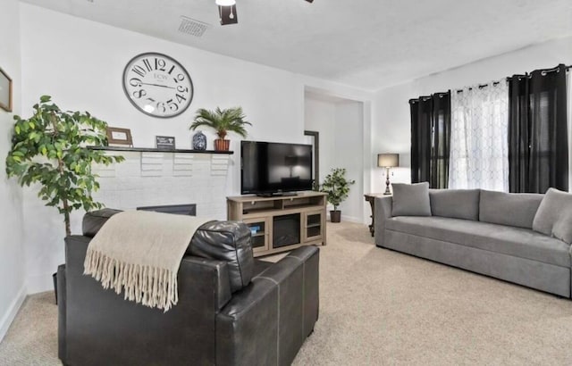 carpeted living room featuring a fireplace and ceiling fan