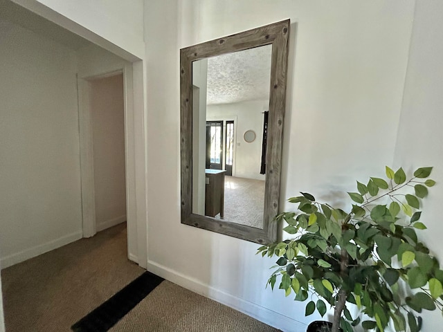 corridor with a textured ceiling and carpet flooring