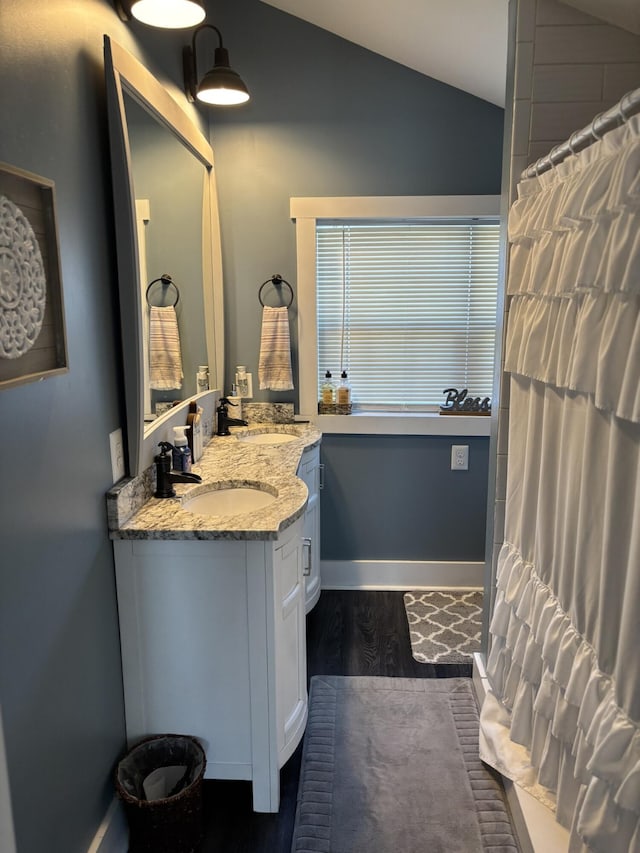 bathroom with hardwood / wood-style flooring, vanity, vaulted ceiling, and walk in shower