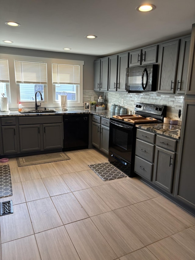 kitchen with sink, backsplash, black appliances, and dark stone counters