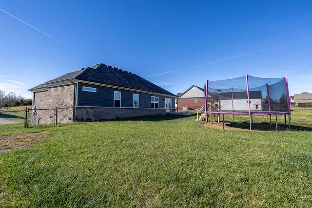 back of property featuring a lawn and a trampoline