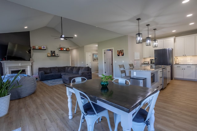 dining space featuring ceiling fan, lofted ceiling, and light wood-type flooring