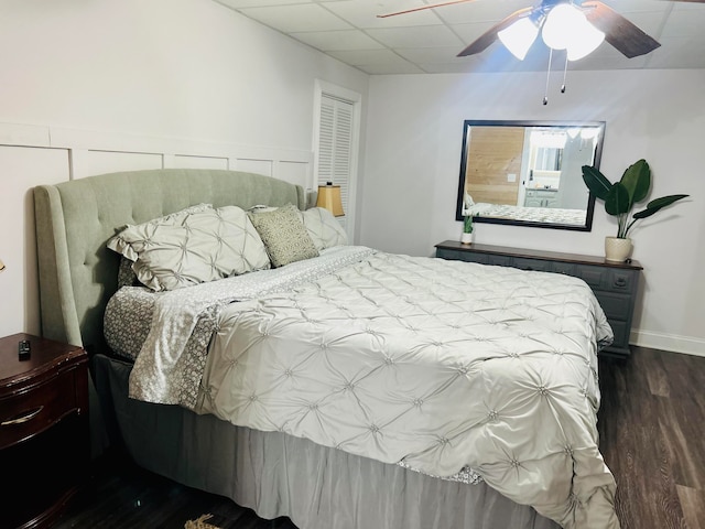 bedroom with a paneled ceiling, ceiling fan, and dark wood-type flooring