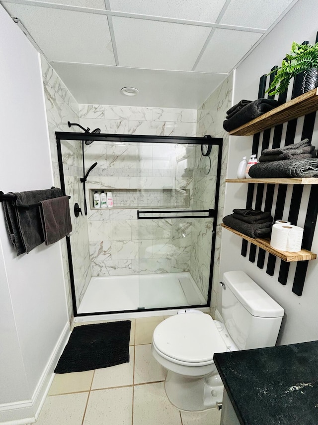 bathroom featuring a paneled ceiling, tile patterned flooring, an enclosed shower, and toilet