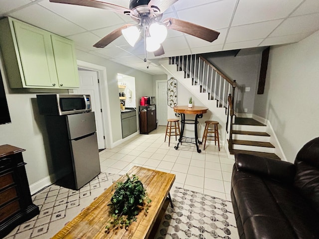 kitchen featuring a paneled ceiling, light tile patterned flooring, stainless steel appliances, and green cabinetry